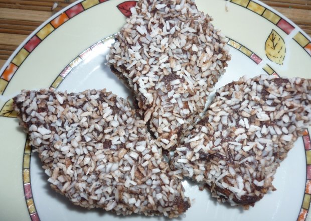 Fotografia przedstawiająca biszkopt w czekoladzie i wiórkach kokosowych
