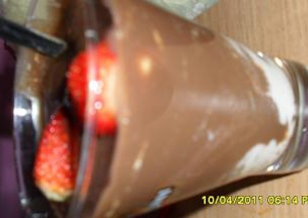 Fotografia przedstawiająca Budyń czekoladowy z bitą śmietaną i truskawkami