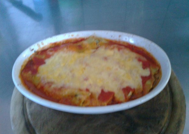 Fotografia przedstawiająca Canneloni z farszem szpinakowym zapiekany w sosie pomidorowym z żółtym serem