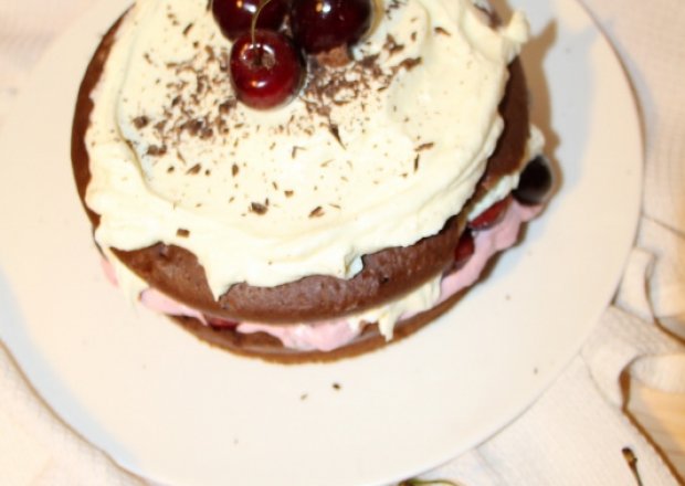 Fotografia przedstawiająca Ciasto czekoladowe z bitą śmietaną i czereśniami