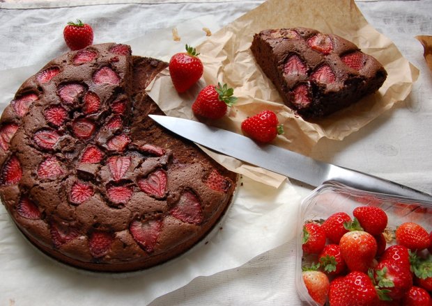 Fotografia przedstawiająca ciasto mocno czekoladowe z truskawkami