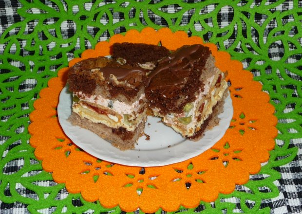 Fotografia przedstawiająca Ciasto z kremem, ciasteczkami, bitą śmietaną i galaretką.