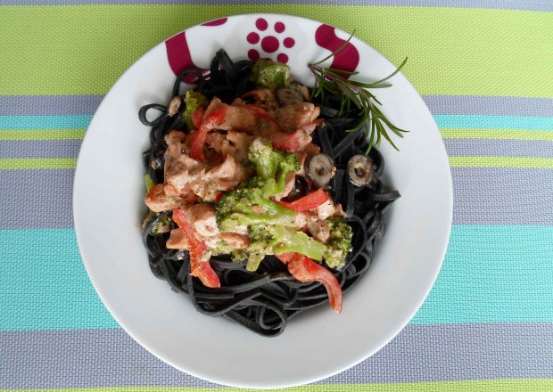 Fotografia przedstawiająca Czarne tagliatelle z łososiem i warzywami na ostro