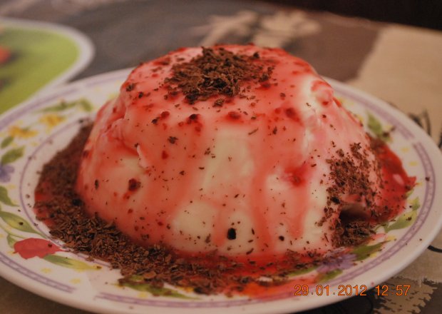 Fotografia przedstawiająca deser smietankowy z sosem truskawkowym