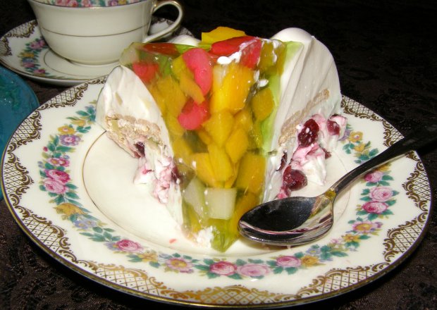 Fotografia przedstawiająca deser twarogowy z cukrem miętowym,żurawiną,owocami i galaretką