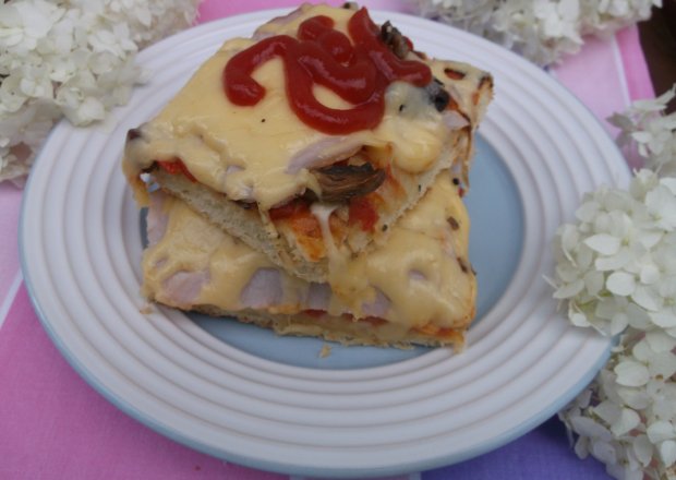 Fotografia przedstawiająca Domowa pizza z papryką,cebulą,pieczarkami i szynką.
