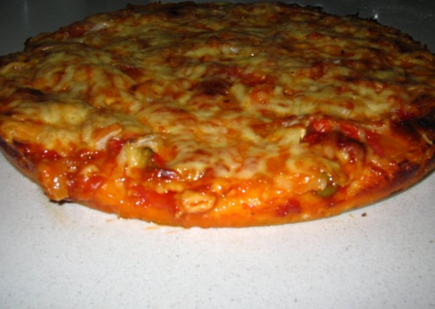 Fotografia przedstawiająca Domowa pizza z pomidorami i czarnymi oliwkami
