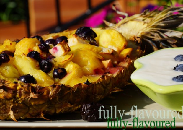 Fotografia przedstawiająca Grillowana sałatka owocowa z miodem spadziowym  i trójniakiem podawana w ananasie z miodowym sose...