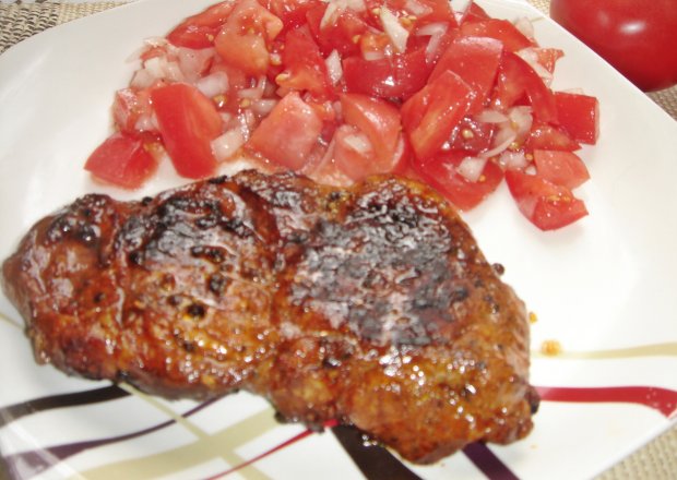 Fotografia przedstawiająca Grillowane steki karkowe teriyaki podane z lekką sałatką z pomidorów malinowych i cebuli czosnkowej