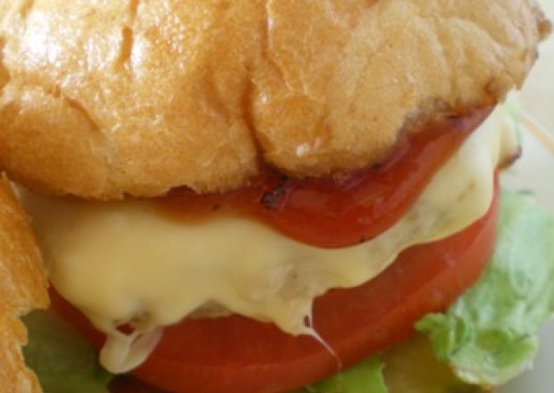 Fotografia przedstawiająca Hamburger z serem, pomidorem i ogórkiem kiszonym