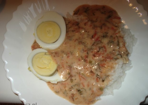 Fotografia przedstawiająca jajka na twardo podane z sosem koperkowo-pomidorowym i ryżem