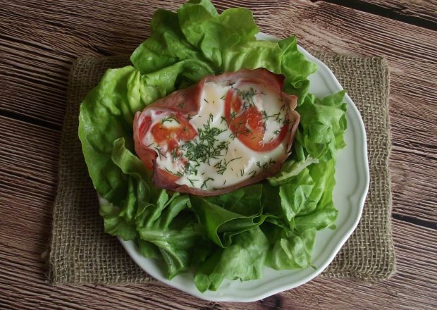 Fotografia przedstawiająca Jajka zapiekane w szynce z pomidorem i koperkiem podane na sałacie
