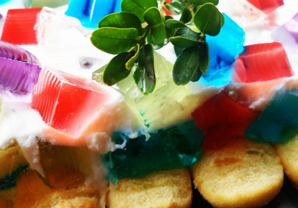 Jogurtowiec z kolorowymi kostkami galaretki na biszkoptach foto