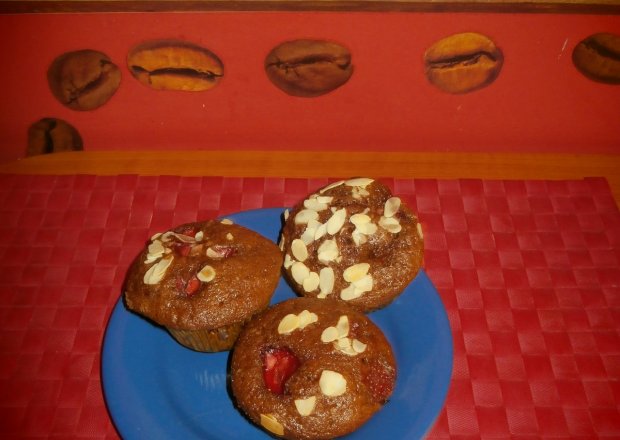 Fotografia przedstawiająca Kakaowe muffinki z truskawkami i płatkami migdałowymi.