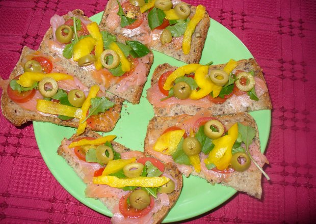 Fotografia przedstawiająca Kanapki z łososiem wędzonym ,oliwkami , pomidorem i papryką