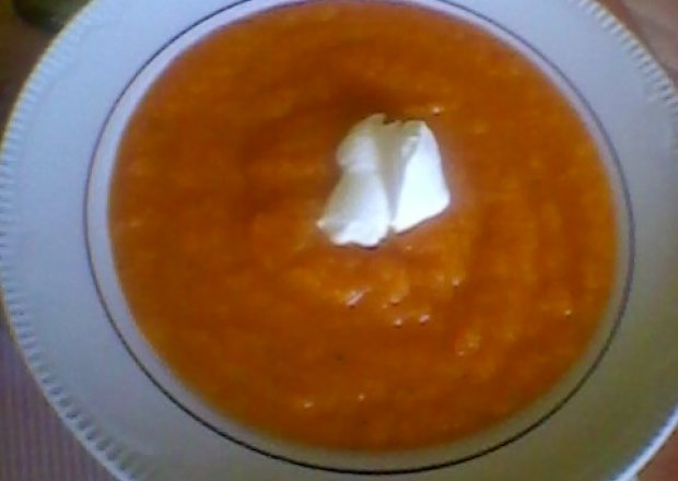Fotografia przedstawiająca kremowa  zupa z dyni ze  śmietaną