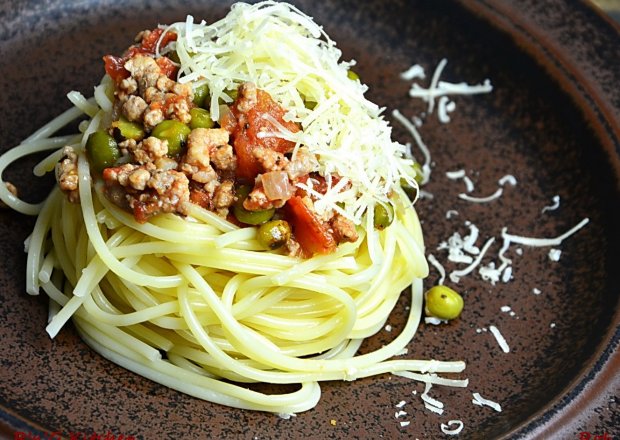 Fotografia przedstawiająca Makaron spaghetti z sosem pomidorowym, zielonym groszkiem i mieloną karkówką