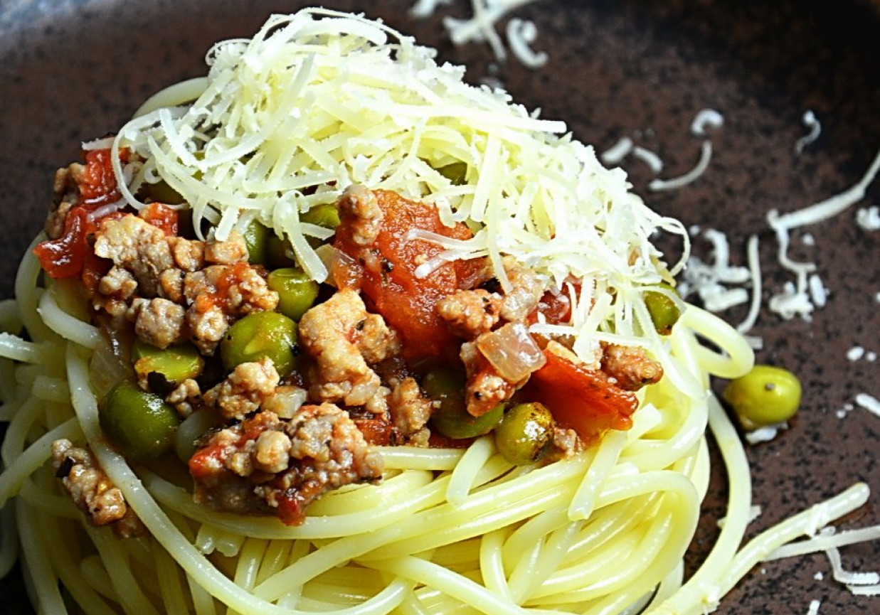 Makaron spaghetti z sosem pomidorowym, zielonym groszkiem i mieloną karkówką foto