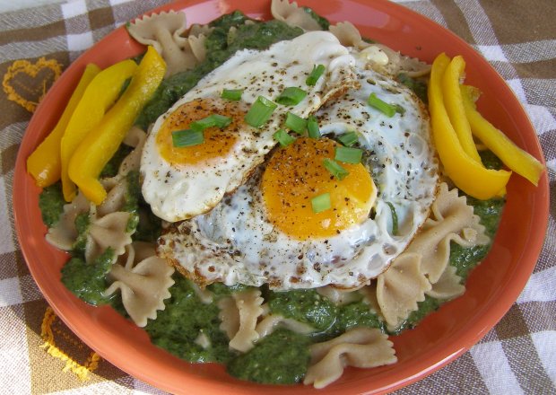 Fotografia przedstawiająca makaron z pełnego ziarna z jajkami sadzonymi z sosem szpinakowym na jogurcie...