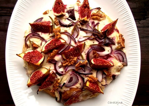 Fotografia przedstawiająca mała pizza z sosem z koziego sera, figami i orzechami