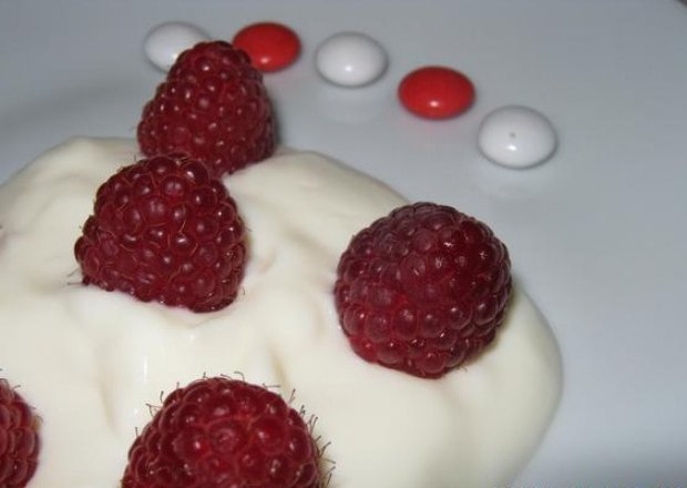 Fotografia przedstawiająca Maliny na kołderce z jogurtu.