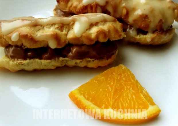 Fotografia przedstawiająca mini eklerki z kremem kawowym i lukrem pomarańczowym
