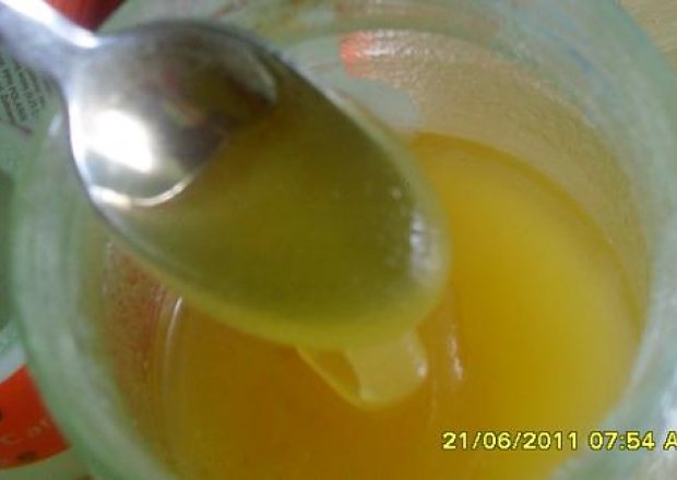 Fotografia przedstawiająca miód pitny z pomarańczą laską cynamonu i goździkami