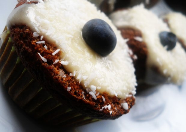 Fotografia przedstawiająca Muffiny piernikowo-makowe w kokosie oraz polewie z białej czekolady i serka waniliowego