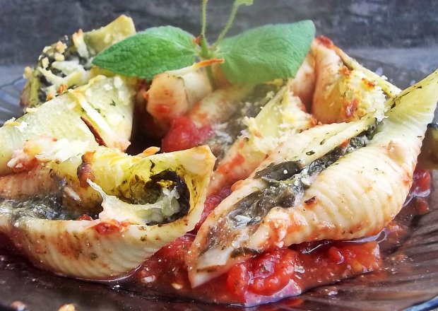 Fotografia przedstawiająca Muszle conchiglioni ze szpinakiem i serem na pomidorach