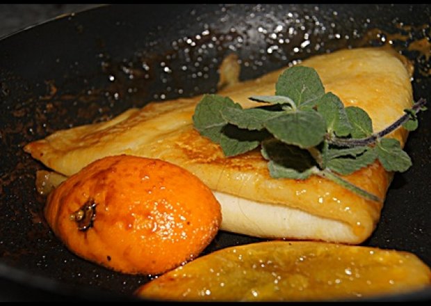 Fotografia przedstawiająca Naleśnik z serem w sosie pomarańczowym ze świeżą miętą