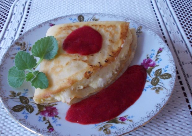 Fotografia przedstawiająca Naleśniki z serem i sosem truskawkowym.
