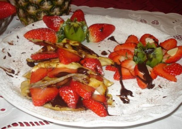 Fotografia przedstawiająca naleśniki z  serkiem owocami i musem czekoladowym