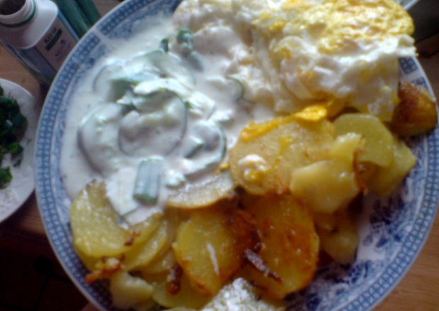 Fotografia przedstawiająca obiad: ziemniaki smażone, jajko sadzone, ogórek z kefirem