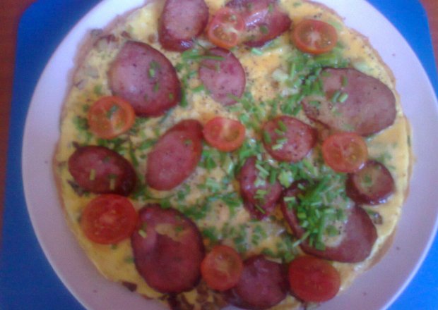 Fotografia przedstawiająca omlet z kiełbasami, pomidorami cherry i szczypiorkiem