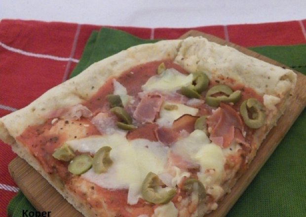 Fotografia przedstawiająca Pełnoziarnista pizza z serem, szynką i oliwkami