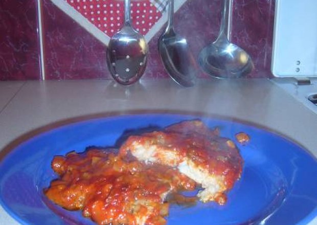 Fotografia przedstawiająca Pieczona ryba w sosie pomidorowym z czosnkiem, cebulą i koperkiem.