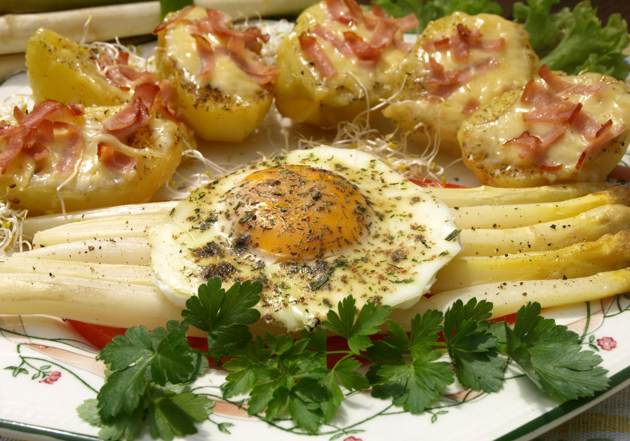 Pieczone ziemniaki z serem i szynką ze szparagami i jajkiem na pomidorze foto
