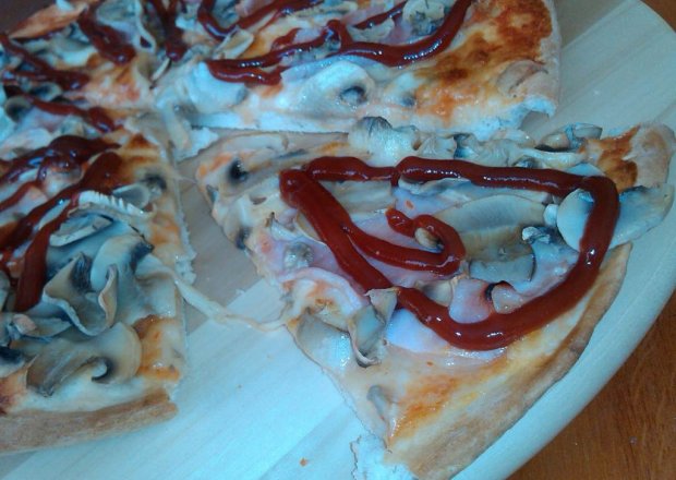 Fotografia przedstawiająca Pikantna okrągła pizza z szynką pieczarkami i mozzarellą