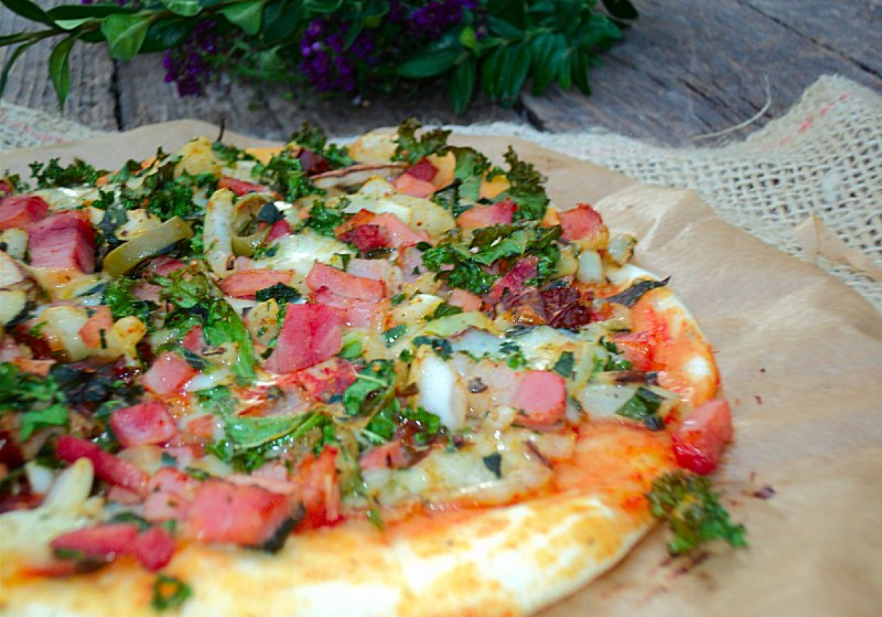 Pizza na cienkim cieście z jarmużem, boczkiem, suchą kiełbasą i mozzarellą  foto