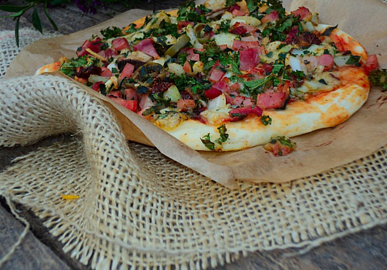 Pizza na cienkim cieście z jarmużem, boczkiem, suchą kiełbasą i mozzarellą  foto