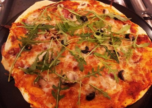 Fotografia przedstawiająca Pizza na cienkim cieście z szynką parmeńską i rukolą