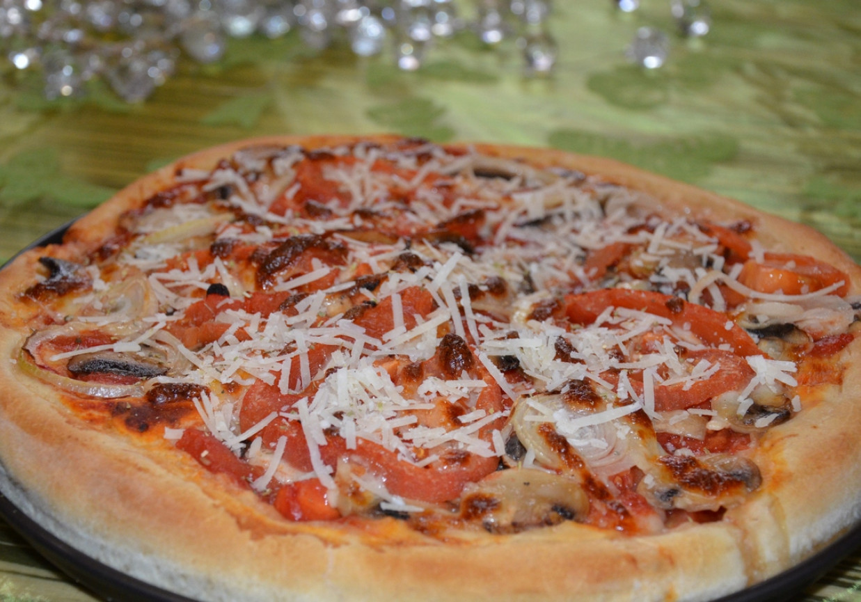 Pizza na pełnoziarnistym cieście z pieczarkami, cebulą, pomidorami i serem grana padano foto