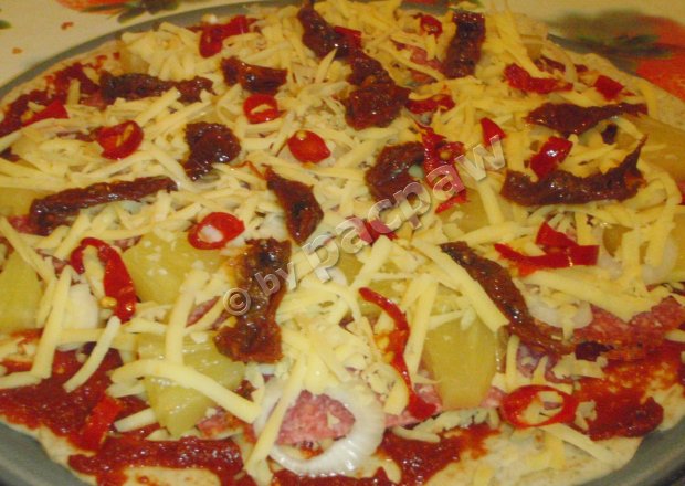Fotografia przedstawiająca Pizza pełnoziarnista z salami pieprzowym, pomidorami suszonymi i papryczkami piri-piri