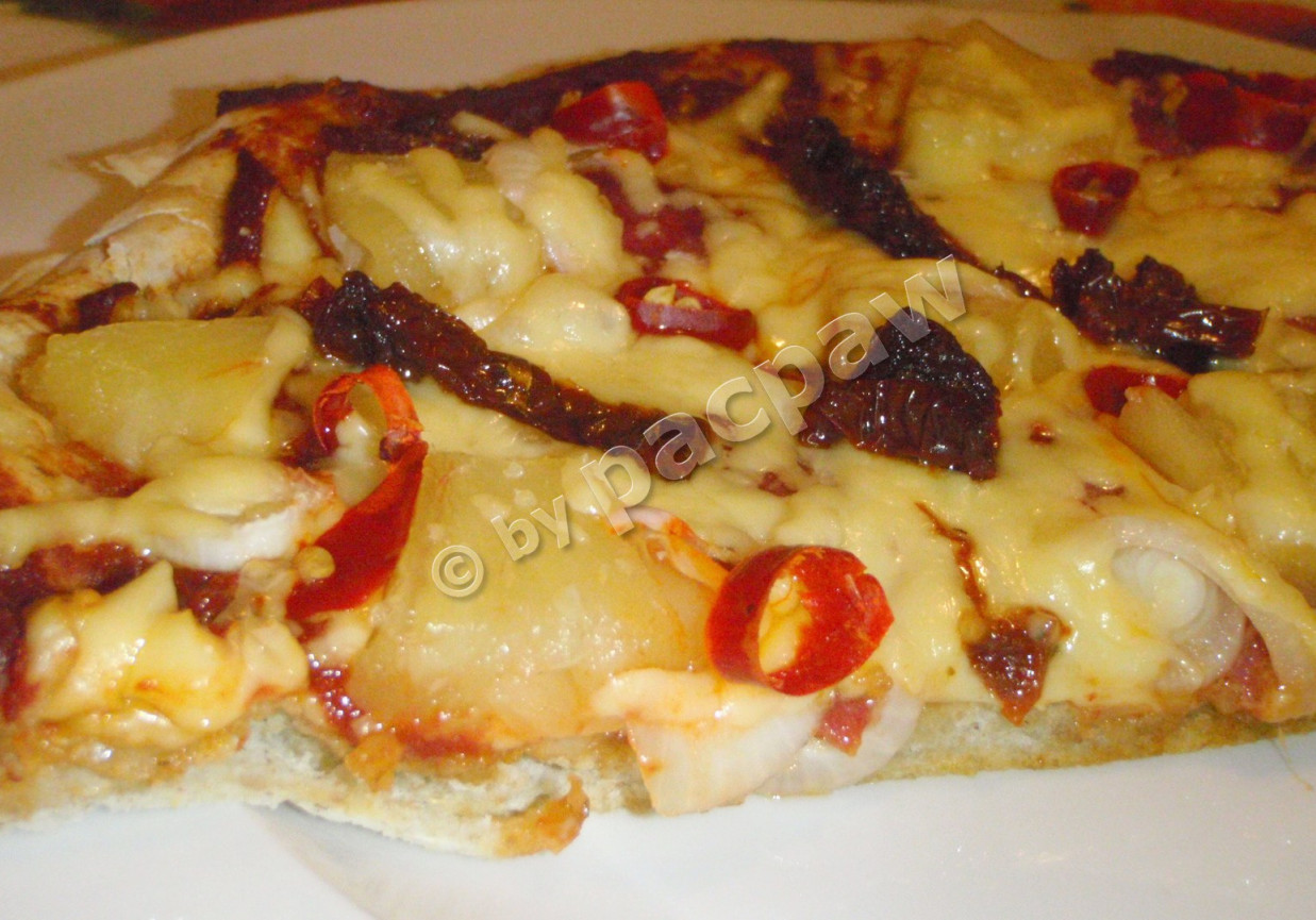 Pizza pełnoziarnista z salami pieprzowym, pomidorami suszonymi i papryczkami piri-piri foto
