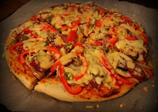 Fotografia przedstawiająca Pizza puszysta z kiełbasą, papryką i oliwkami