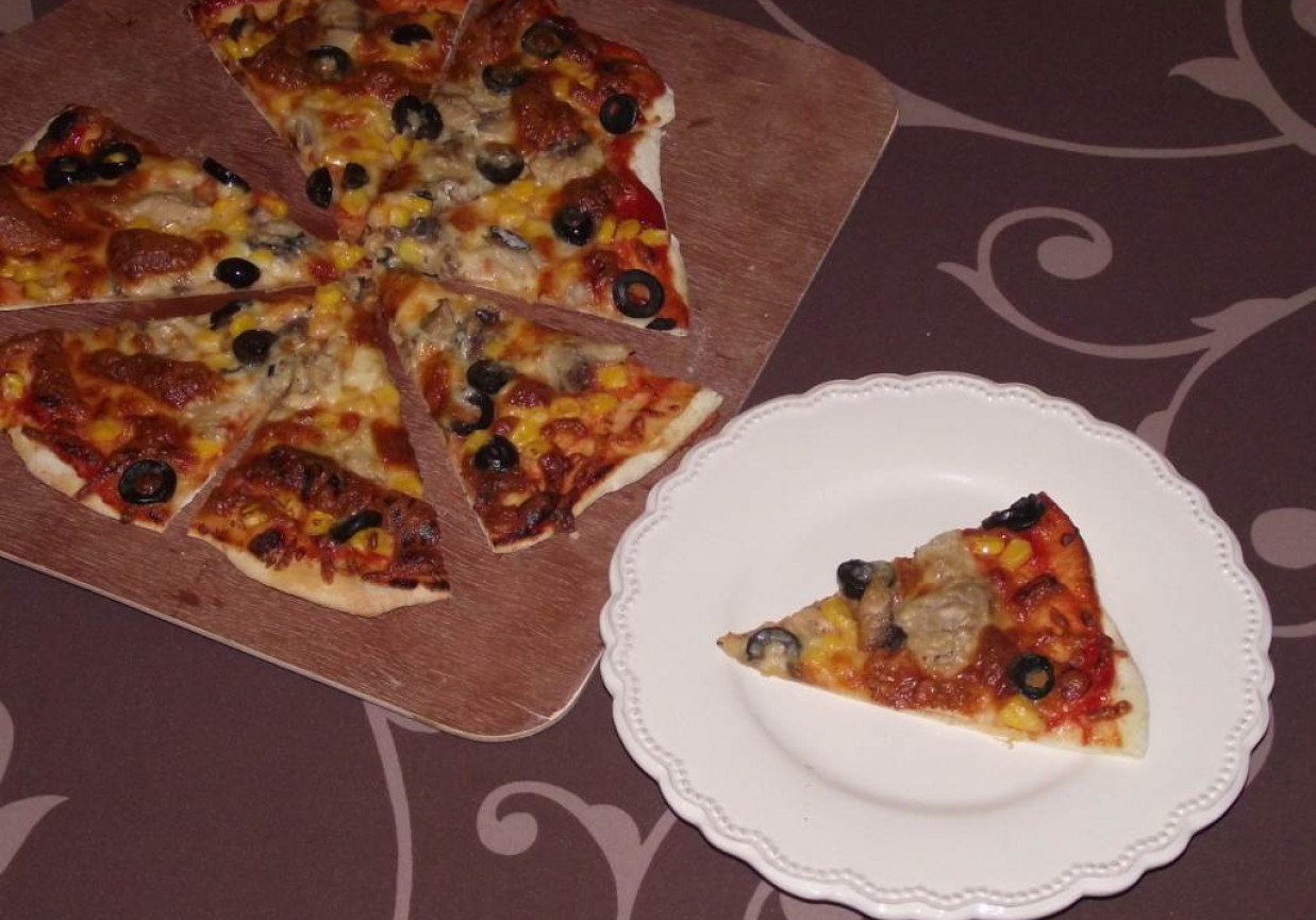 Pizza z kamienia na cienkim cieście z makrelą, kukurydzą i oliwkami  foto