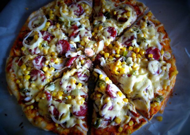Fotografia przedstawiająca Pizza z kiełbasą, kukurydzą, cebulą i ostrą papryczką