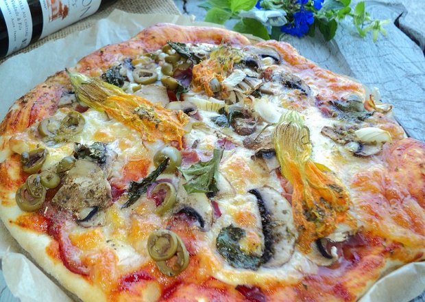Fotografia przedstawiająca Pizza z mozarellą, pieczarkami, sosem chilli , kwiatami cukinii i botwinką