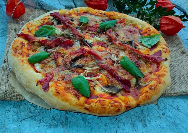 Fotografia przedstawiająca pizza z mozarellą szynką parmeńską  pieczarkami