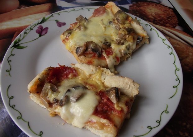 Fotografia przedstawiająca Pizza z mozzarellą, szynką i pieczarkami.